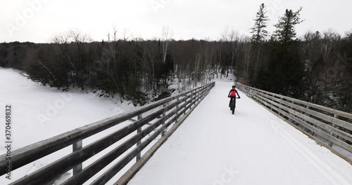 Fat bike in winter. Fat biker riding bicycle in the snow in winter. Woman living healthy outdoor active winter sports lifestyle. Mont Tremblant, Quebec, Canada. photo