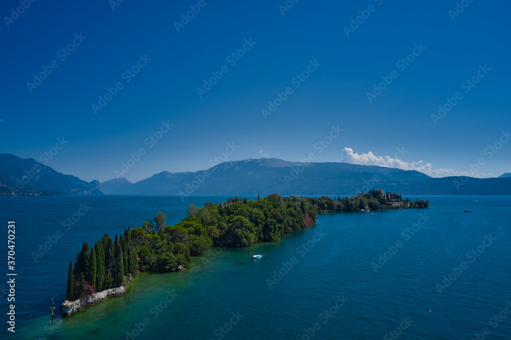 Obraz premium Aerial view of the island Garda, Lake Garda, Italy. Is the biggest island on Lake Garda. In the background Alps, blue sky.