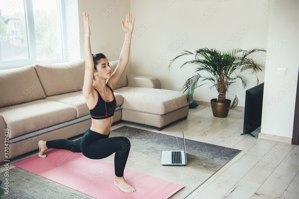 Stretching caucasian woman doing fitness at home wearing sportswear and using a laptop on the floor Stretching caucasian woman doing fitness at home wearing sportswear and using a laptop on the floor
