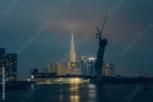 Raining view of skyline with landmark 81 skyscraper, a new cable-stayed bridge is building connecting Thu Thiem peninsula and District 1 across the Saigon River.