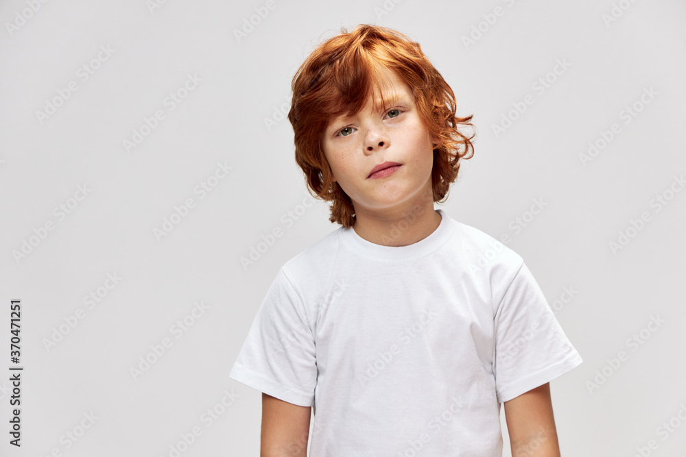 Portrait of a red-haired boy in a white T-shirt with his head on one side Portrait of a red-haired boy in a white T-shirt with his head on one side