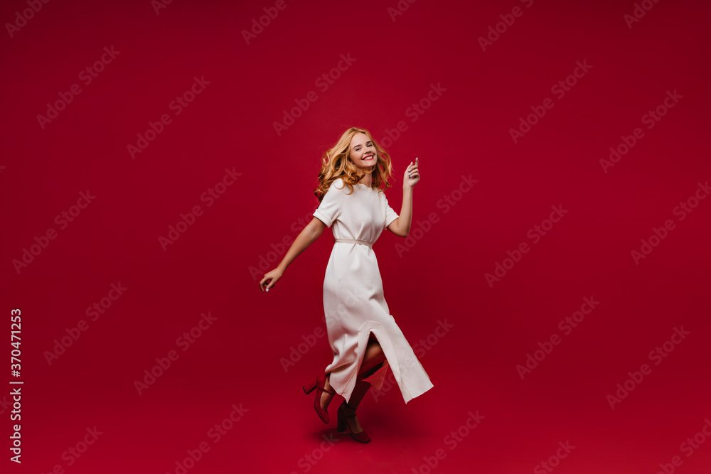 Full-length portrait of inspired fair-haired lady dancing at party. Appealing caucasian girl in long dress enjoying event.