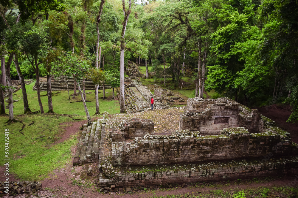 aerial landscape of turist with red jacket on top of Mayan ruins in Copan surrounded by jungle and green vegetation