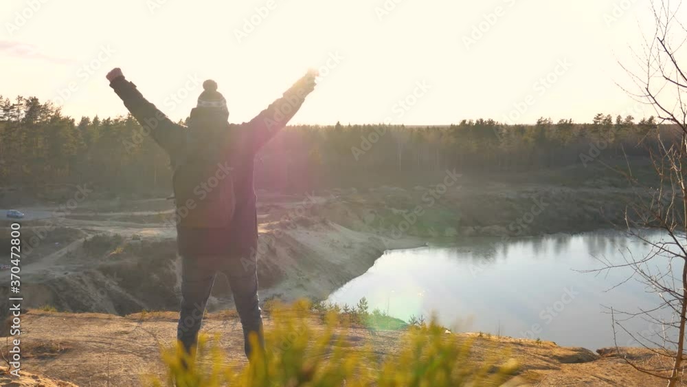 A man at sunset looks at the sun and rejoices in the victory. Celebrating and achieving the goal. A man at sunset looks at the sun and rejoices in the victory. Celebrating and achieving the goal.