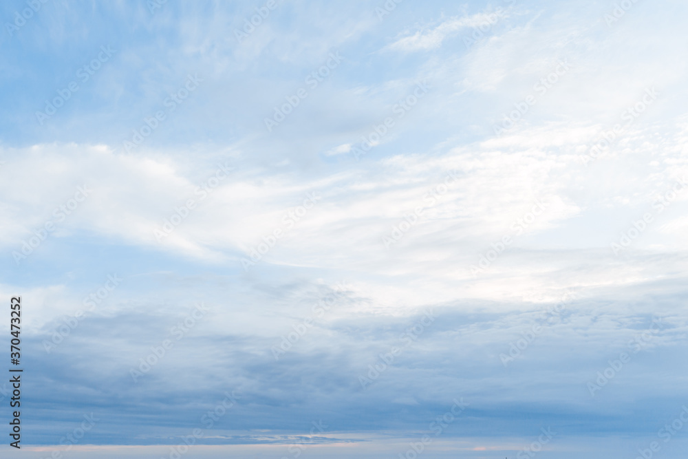 Blue sky with white clouds. Background from the cloudy sky. Long and stretched clouds in the sky.Blue sky with long clouds for background. 