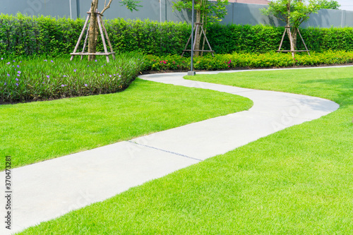 Gray walkway on green grass lawn in garden, sand washed finishing pavement photo