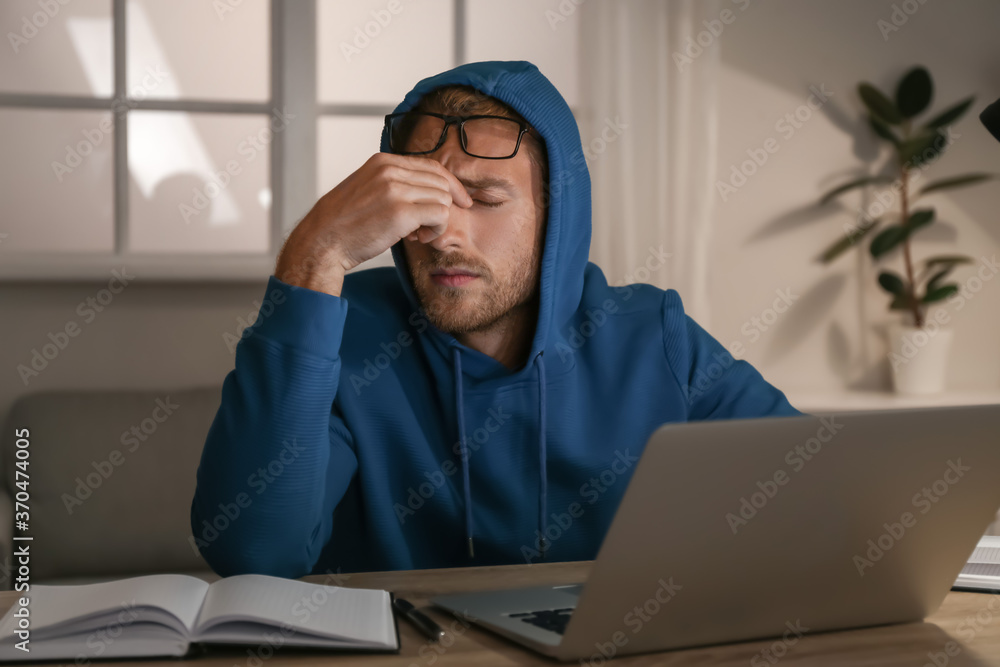 Tired male student using laptop for online learning at home Tired male student using laptop for online learning at home