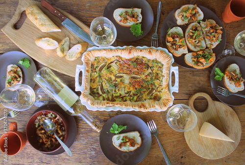 Flat-lay of people eating and drinking wine. Casserole with cheese and mushrooms. Mushroom tart
