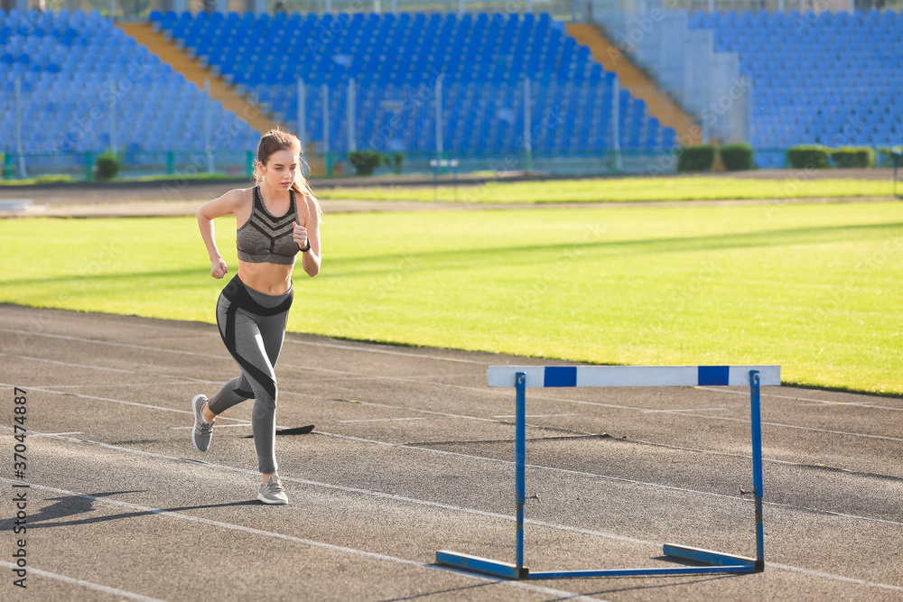 Sporty young woman running in the stadium