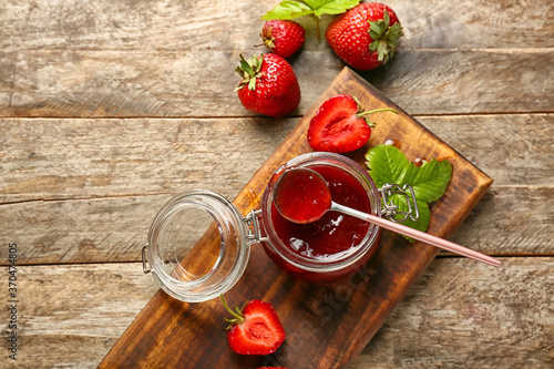 Jar of tasty strawberry jam on table