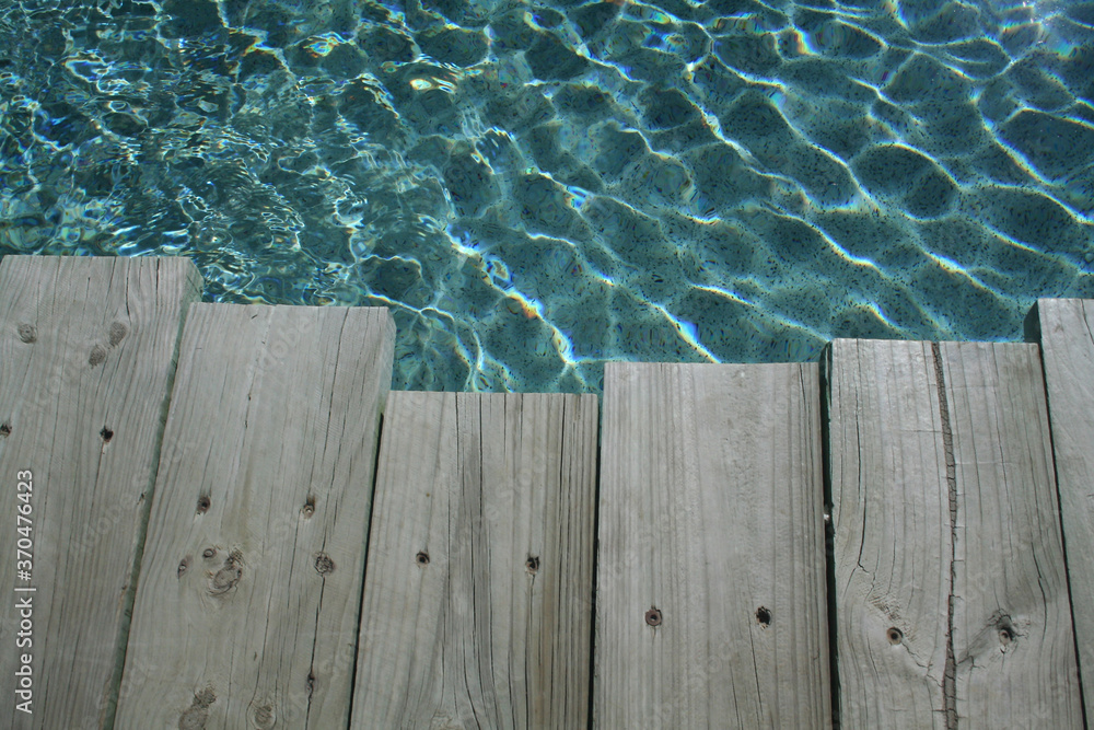 The side of a backyard swimming pool with lovely clear water The side of a backyard swimming pool with lovely clear water