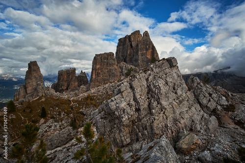 Rugged and rocky alpine mountain ranges with cloudy blue sky above in The Dolomites. These iconic mountain peaks are located at Cinque Torri in the Tyrol region of Italy.
