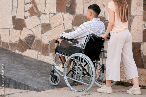 Young woman and her husband in wheelchair on ramp outdoors