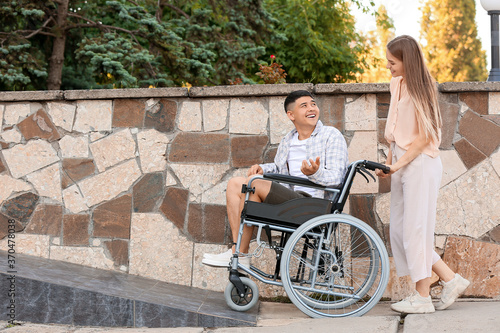 Young woman and her husband in wheelchair on ramp outdoors