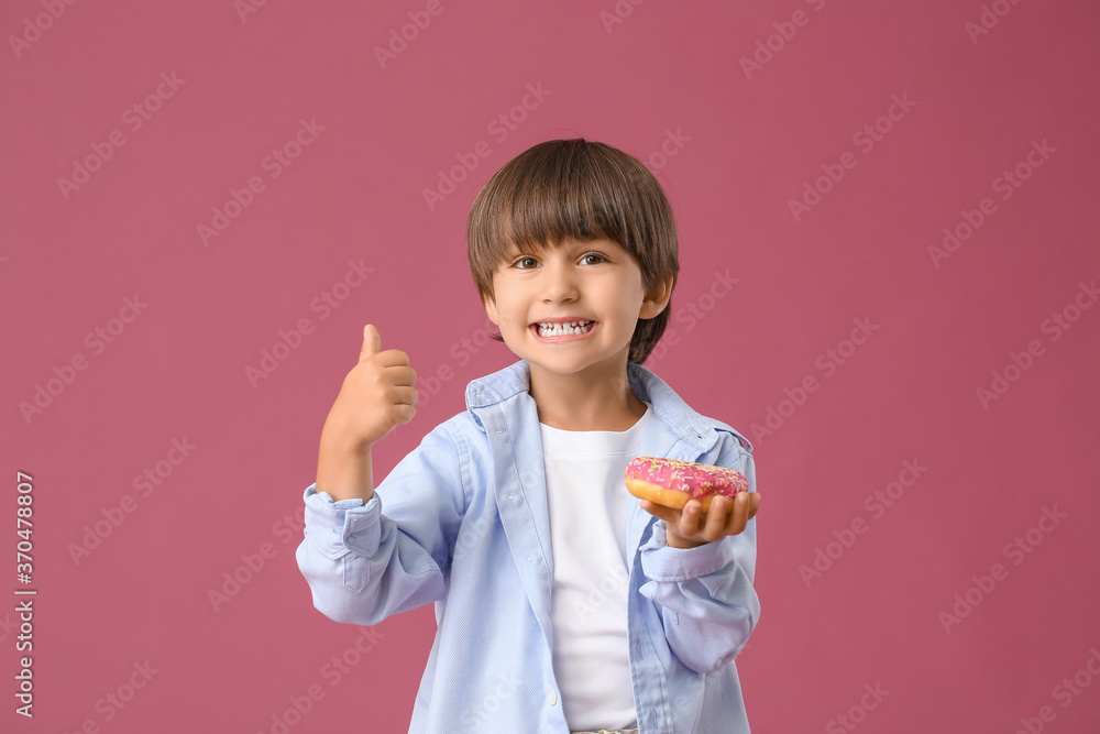 Funny little boy with donut showing thumb-up gesture on color background Funny little boy with donut showing thumb-up gesture on color background