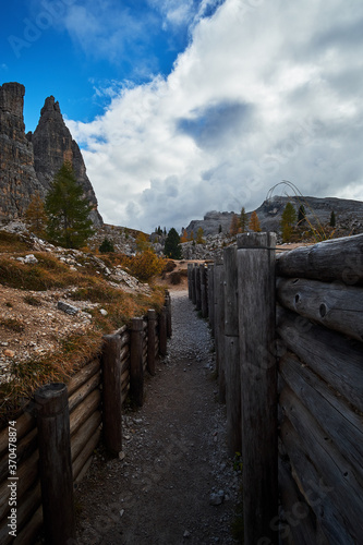 Historic World War 1 trenches and structures surrounded by rocky mountain landscapes with cloudy blue sky above. Located in The Dolomites mountains of Cinque Torri near Cortina in Italy.