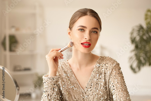 Young woman doing makeup at...