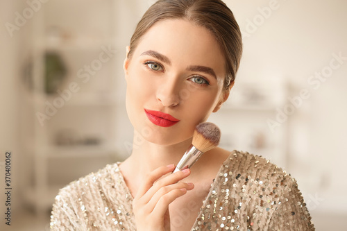 Young woman doing makeup at...