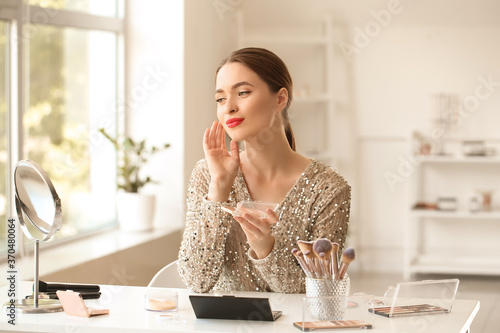 Young woman doing makeup at...