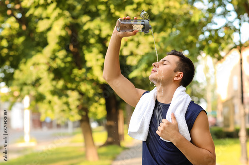 Sporty young man pouring wa...