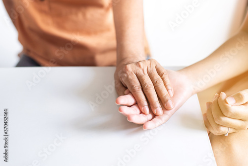 Woman holding hands to elderly with alzheimer disease at home,Adult social care concept