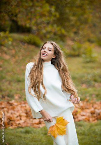 Autumn vogue. Young stylish hipster girl wearing modern dress in urban park smiling happy. Caucasian female model. Fall fashion.