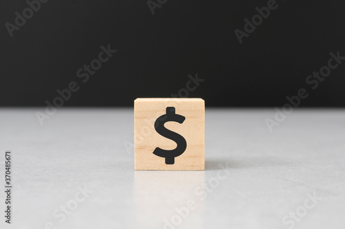 dollar sign on wooden cube block cement top black background