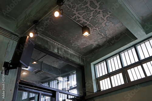 Interior architecture and ceiling design of industrial loft building decorated with modern lamps, glass windows and wall speakers