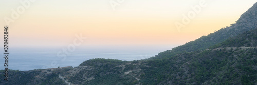 dusk mountain landscape with views of the Mediterranean sea and cloudless sky. Golden hour, haze or fog. banner