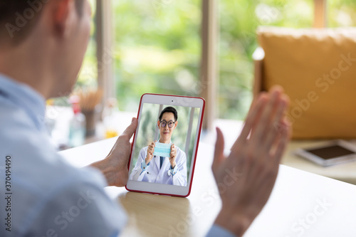 Businessman with having video call with male doctor on tablet at home to prepare for Covid 19.Social distancing or new normal style.