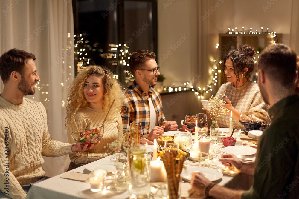 holidays, celebration and people concept - happy smiling friends having christmas dinner party at home in evening holidays, celebration and people concept - happy smiling friends having christmas dinner party at home in evening
