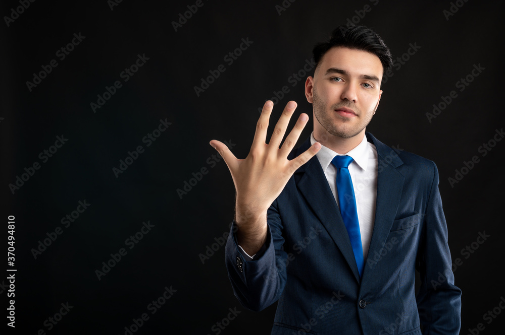 Portrait of business man wearing blue business suit and tie showing five fingers Portrait of business man wearing blue business suit and tie showing five fingers