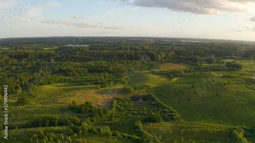 Flying over beautiful countryside landscape with field and trees, Latvian nature, summer sun.