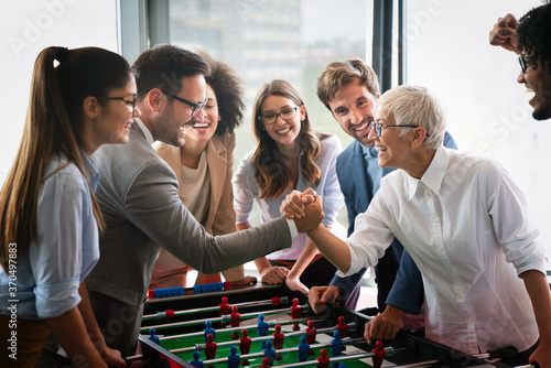 Employees playing table soccer indoor game in the office during break time photo