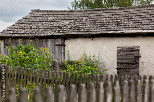 Fototapeta Naklejka Na Ścianę i Meble -  Wiejski budynek gospodarczy i stary płot z drewnianych sztachet.
