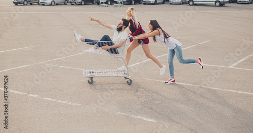 Young women pushing cart with male friend