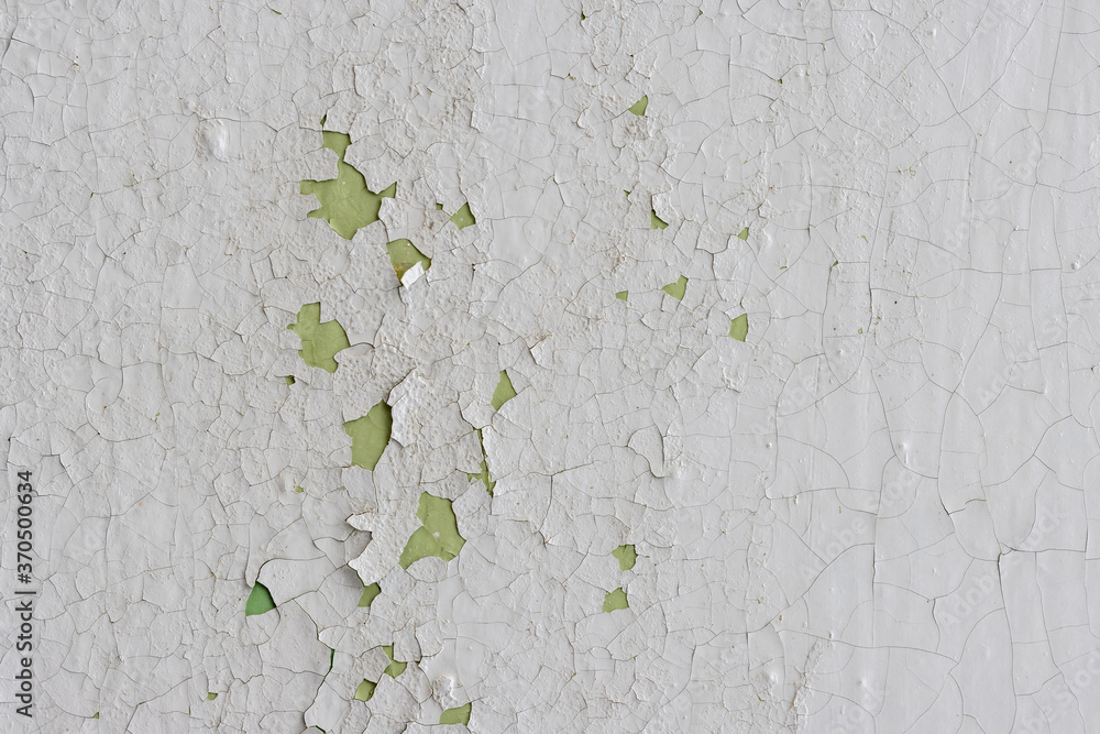 White peeling paint on the wall. Old concrete wall with cracked flaking