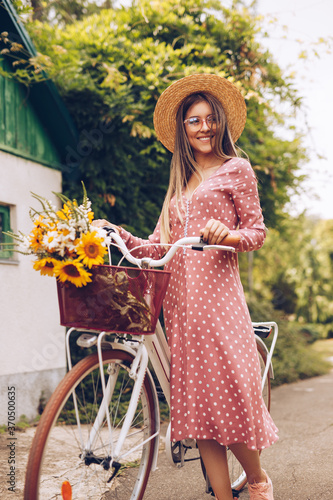 Cheerful stylish woman with bicycle and flowers