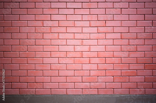 The brick wall of red color with a cement base on the bottom. Ideal for use as a design background or for adding text, brick wall patterns.