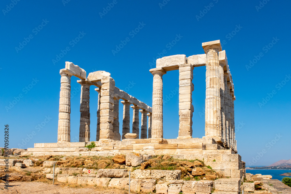 The ancient Greek Temple of Poseidon at Cape Sounion, doric columns and ruins on the hill with crystal blue sky background.
