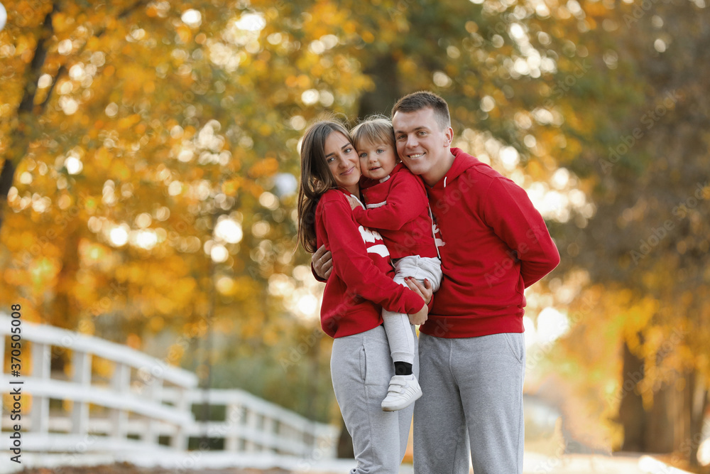 Happy young family in the autumn park. People having fun in nature. Family bonds outside. Mother, father and child smiling while spending free time outdoors Happy young family in the autumn park. People having fun in nature. Family bonds outside. Mother, father and child smiling while spending free time outdoors