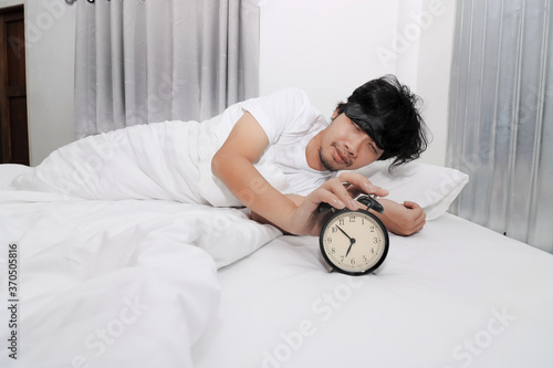 Hands of sleepless and desperate young man turns off the alarm clock waking up at morning.