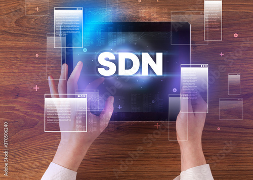 Close-up of a hand holding tablet with SDN abbreviation, modern technology concept
