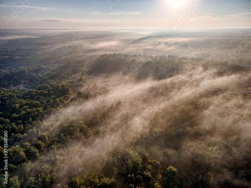 Misty forest hills with morning fog and sun rays. photo