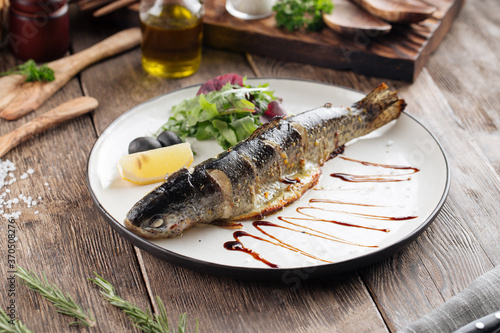Gourmet grilled fish with greens lemon and olives