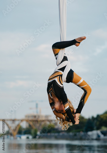 Child girl aerialist performs acrobatic tricks on hanging aerial silk. photo