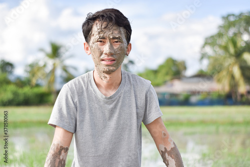 Close up of a man's face and hands covered in mud