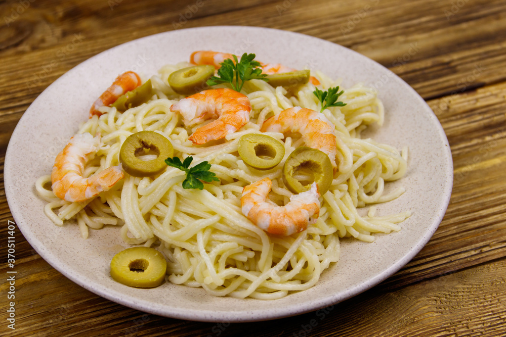Spaghetti pasta with prawns, green olives and parsley on wooden table Spaghetti pasta with prawns, green olives and parsley on wooden table