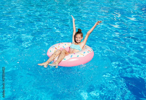 Cute smiling little girl in swimming pool with rubber ring