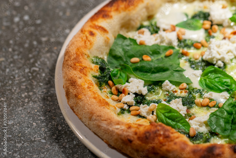 Vegetarian spinach pizza with ricotta cheese and pine nuts on a stone background. Vegetarian spinach pizza with ricotta cheese and pine nuts on a stone background.